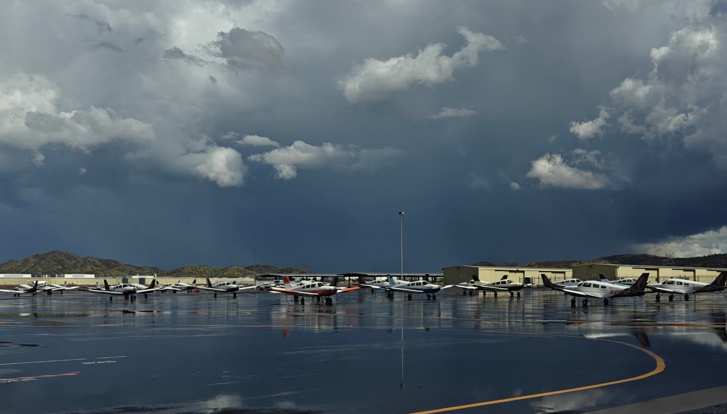 Training aircraft on a rain-soaked ramp at Phoenix Deer Valley under a monsoon storm cloud